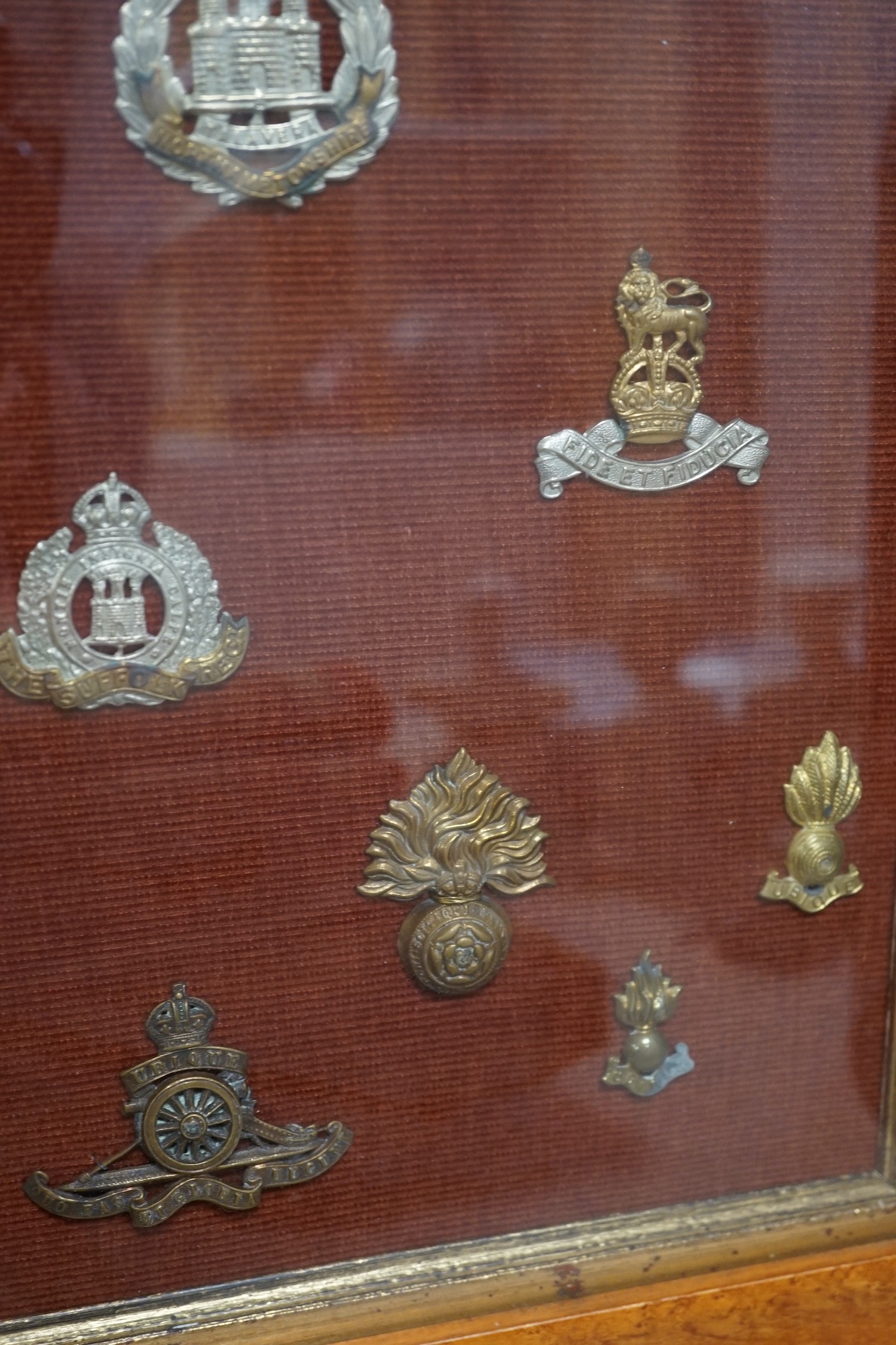 A framed collection of military cap Badges